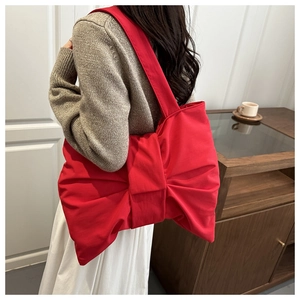 Grande borsa tote rossa in tela a forma di fiocco indossata a spalla da una modella