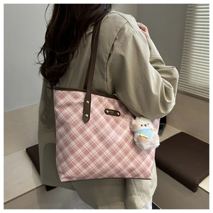 Dettaglio borsa shopper a scacchi rosa con manici in pelle e ciondolo orsetto