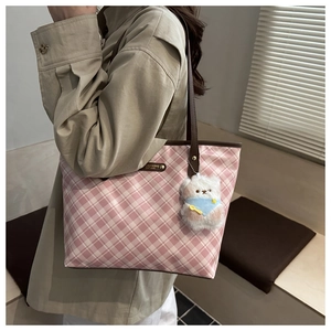 Dettaglio borsa tote a scacchi rosa con manici in pelle marrone e ciondolo orsetto bianco