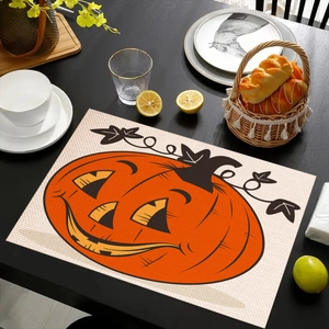 Detail eines Leinen-Halloween-Platzsets mit orangem Kürbisdruck auf schwarzem Holztisch