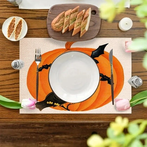 Halloween pumpkin and bat pattern linen placemat on dark wooden dining table