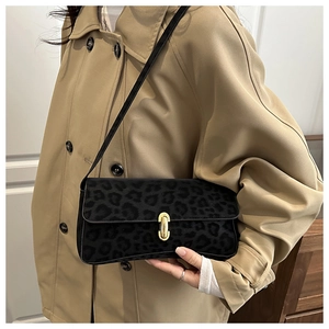 Borsa baguette leopardata con fibbia dorata su un trench coat kaki