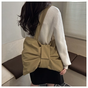 Vista posteriore di una modella con la borsa a tracolla in tela kaki a forma di fiocco