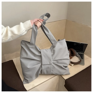 Dettaglio di una borsa a mano grigia a forma di fiocco in un ambiente di studio moderno