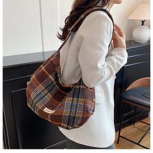 Close-up of vintage plaid hobo bag with moon-shaped design and wide shoulder strap