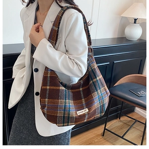 Detail of vintage brown plaid hobo bag with thick textured fabric and logo patch