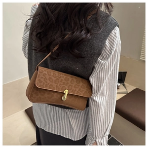 Dettaglio borsa a spalla leopardata con fibbia dorata su outfit a camicia a righe