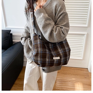 Close-up of oversized plaid tote bag in dark brown and blue gray worn by model