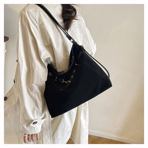 Dettaglio di una borsa hobo in pelle scamosciata nera con occhielli dorati sulla modella