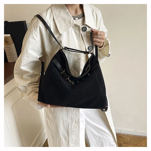 Dettaglio di una borsa tote grande in camoscio nero con tracolla in pelle e fibbie oro