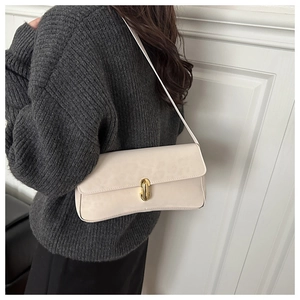 Elegante borsa sottobraccio in pelle crema con chiusura dorata su modella