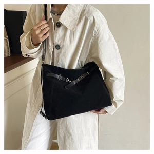 Dettaglio borsa a tracolla in pelle scamosciata nera con fibbia indossata su trench beige