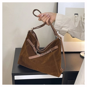 Dettaglio della texture in pelle scamosciata marrone scuro e fibbia dorata della borsa tote