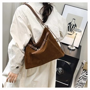 Dettaglio di una grande borsa tote in pelle scamosciata marrone sulla spalla di una modella