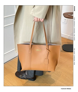 Detailed view of a brown leather tote bag featuring golden text logo and slim straps
