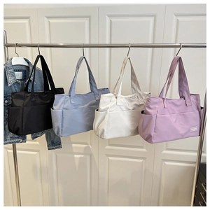 Dettaglio di borse tote in nylon appese in fila con design a tasche multiple