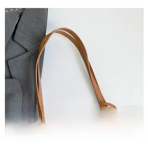 Close-up of the smooth faux leather strap and stitching on a caramel tote bag