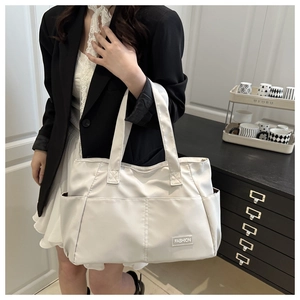 Modella che mostra una grande borsa tote in nylon beige per pendolari in casa accogliente
