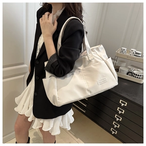 Dettaglio di una borsa tote crema con etichetta moda e tasca laterale per ufficio
