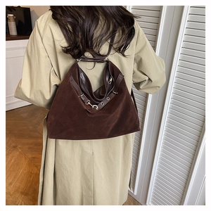 Dettaglio della borsa hobo marrone scuro con tracolla in pelle e ganci dorati su trench