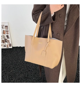Detail view of large apricot faux leather tote bag with elegant gold logo lettering