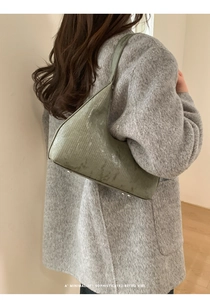 Dettaglio borsa a portafoglio verde goffrata con piedini in metallo e finitura texture