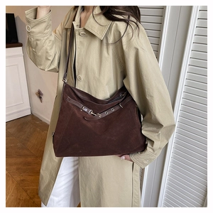 Dettaglio borsa tote in pelle scamosciata marrone con occhielli su un trench color kaki