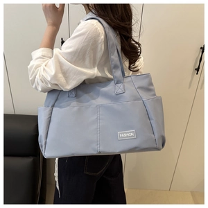 Dettaglio borsa tote in tela celeste con tasche laterali ed etichetta tessuta Fashion