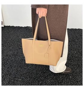 Detail of the high-quality leather tote bag featuring elegant brand lettering and a bag charm
