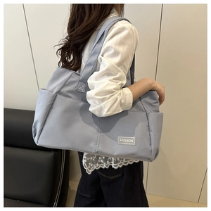 Dettaglio della borsa tote in nylon blu con tasca laterale e marchio alla moda