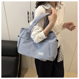 Dettaglio della grande borsa tote azzurra con etichetta fashion e tasca laterale