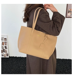 Détail du sac cabas beige en similicuir avec logo doré et pendentif décoratif