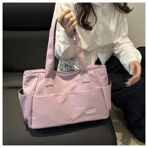 Dettaglio della grande borsa tote in nylon malva con doppie tasche frontali e patch