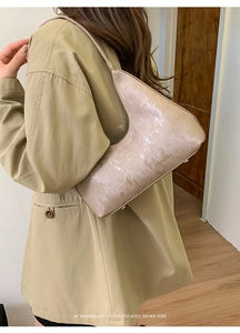 Dettaglio borsa a tracolla beige minimalista con trama a serpente indossata da modella