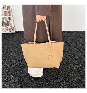 Detail view of the fashion logo and smooth synthetic leather texture on a beige tote bag