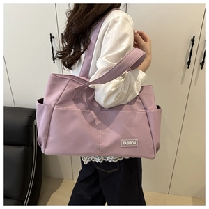 Dettaglio della grande borsa tote in tela lavanda con tasca frontale e etichetta moda sulla spalla