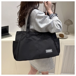 Dettaglio della borsa tote in nylon nero con etichetta Fashion e tasca laterale