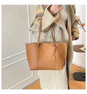 Detail view of large caramel tote bag with gold lettering and stylish side pendant accessory