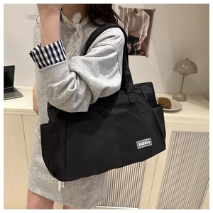 Dettaglio della borsa tote in tessuto nero con logo Fashion e pratica tasca laterale