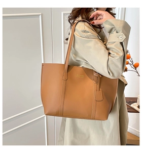Detailed view of brown tote bag with slim shoulder straps and matching leather charm pendant