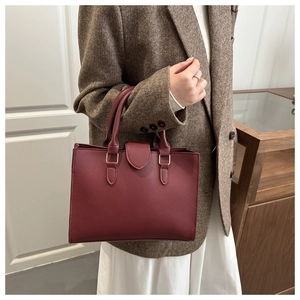 Dettaglio borsa in pelle bordeaux con trama litchi e raffinati ganci in metallo oro