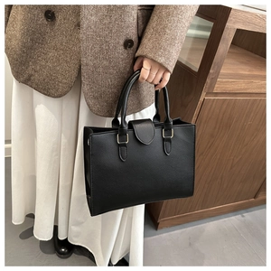 Dettaglio della borsa tote in pelle nera con trama a grana e fibbia in metallo oro
