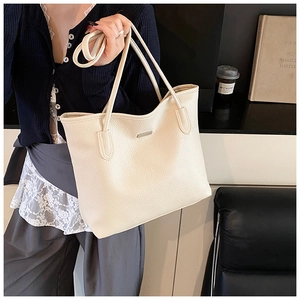 Dettaglio della borsa tote in pelle litchi bianco crema con logo metallico elegante