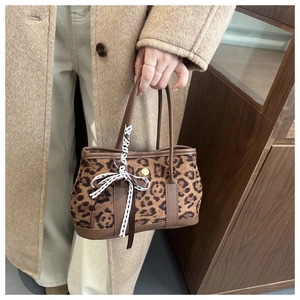 Dettaglio della borsa leopardata con fiocco in pizzo bianco e manici in pelle marrone