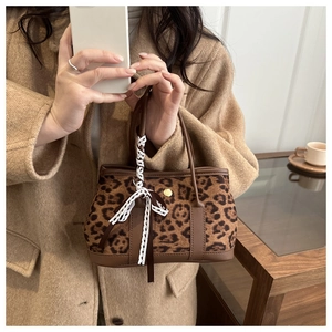Dettaglio borsa leopardata con finiture in pelle marrone e fiocco in pizzo bianco