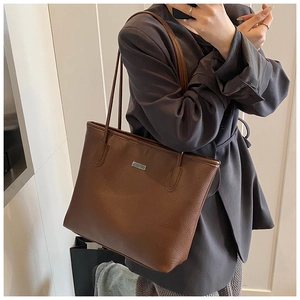 Dettaglio della borsa tote in pelle martellata marrone scuro con placca in metallo
