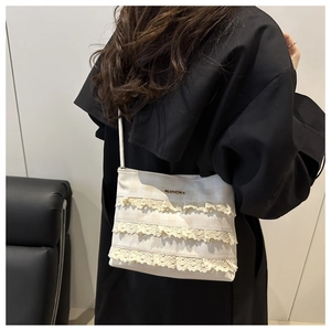 Dettaglio della borsa tote crema a scacchi con balze in pizzo indossata da modella