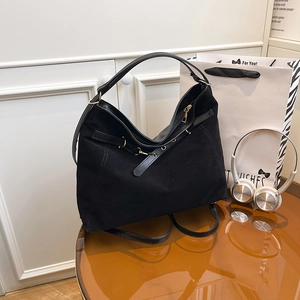 Borsa tote nera minimalista con fibbia in metallo su un accogliente tavolo in legno