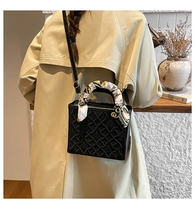 Dettaglio borsa a tracolla nera goffrata con manico avvolto in foulard e hardware dorato