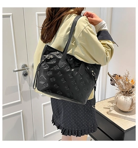 Dettaglio della borsa tote nera con goffratura a fiocchi 3D e fibbie in metallo oro